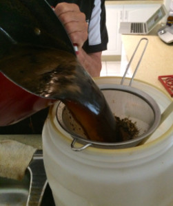 Pan of powder base being poured through a strainer into the barrel
